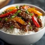 Close-up of beef and pepper rice bowl with sesame garnish