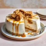 Sliced 2 ingredient Japanese cheesecake no bake topped with Biscoff Lotus cookies and warm cookie butter drizzle on a pastel ceramic plate