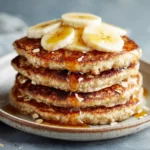Fluffy oatmeal banana pancakes topped with maple syrup and banana slices